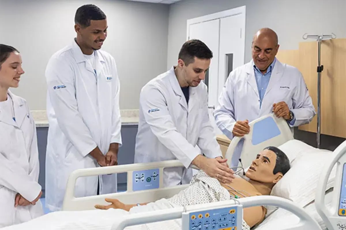 varios estudantes de medicina fazendo um atendimento a um boneco paciente junto de sou professor